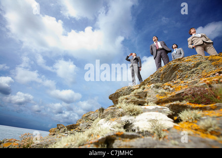 Businessmen standing on cliff edge Stock Photo