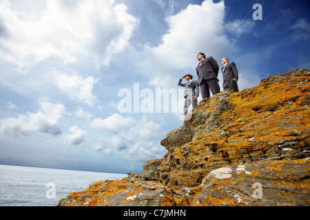 Businessmen standing on cliff edge Stock Photo