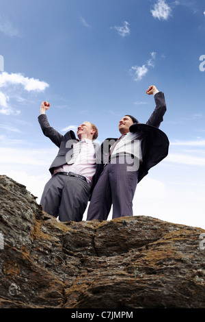 Businessmen cheering on cliff edge Stock Photo