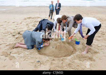 Businessmen building sand castle Stock Photo