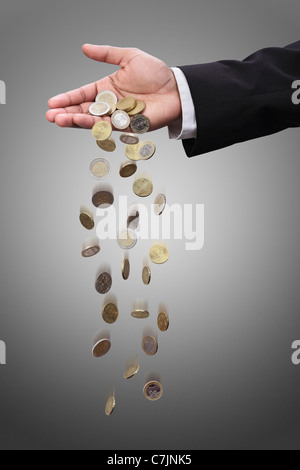 Businessman pouring coins from hand Stock Photo