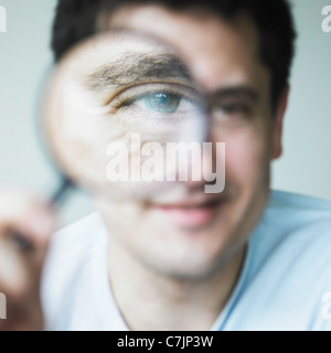 Man looking through magnifying glass Stock Photo