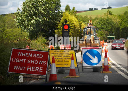 Waiting in car looking out of windscreen at red light traffic signals at roadworks and oncoming vehicles Stock Photo