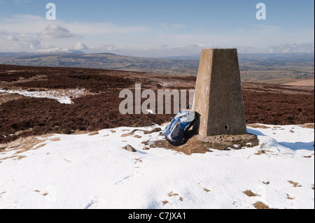 Hilltop summit of Pinhow beacon (trig point, walker's rucksack, sunlit upland moors, scenic rural view, winter snow) - North Yorkshire, England, UK. Stock Photo