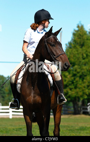 Young girl riding bay horse at a horse show on a summer day Stock Photo