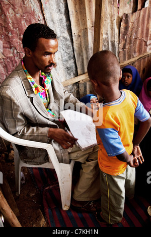 Teacher Faysal marks school work in a small school in Somaliland. Stock Photo