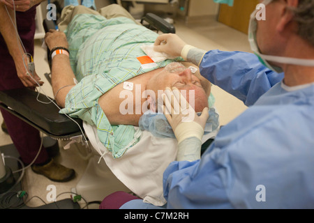 Ophthalmologist using dressing sponge on patient Stock Photo