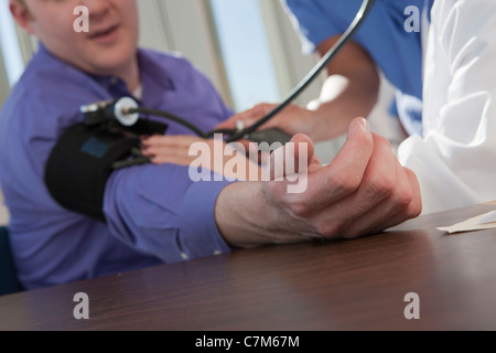 Female doctor and nurse measuring a patient's blood pressure Stock Photo