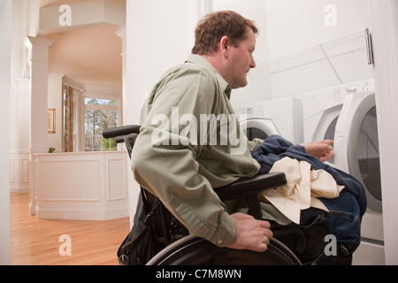 Man with spinal cord injury in a wheelchair doing his laundry at home Stock Photo
