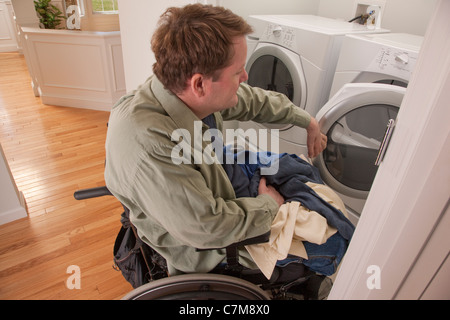 Man with spinal cord injury in a wheelchair doing his laundry at home Stock Photo