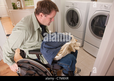 Man with spinal cord injury in a wheelchair doing his laundry at home Stock Photo