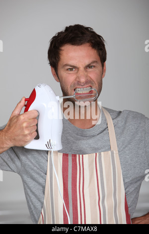 Aggressive chef wielding an electric hand mixer Stock Photo