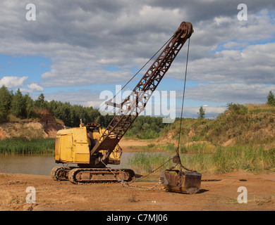 Old yellow excavator in sandy to career. Stock Photo