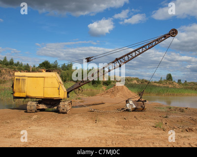 Old yellow excavator in sandy to career. Stock Photo