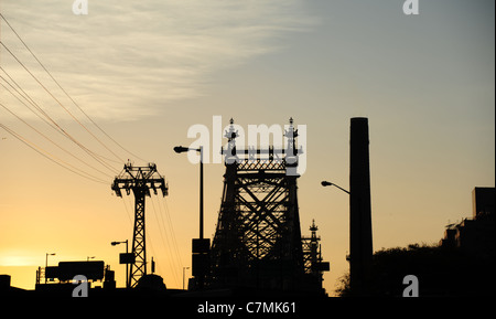 Yellow sunrise silhouette Manhattan end Queensboro Bridge, aerial tramway pylon, factory chimney, from 2nd Avenue, New York City Stock Photo