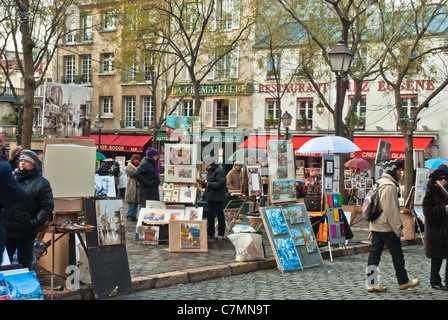 Atmospheric street scene. Gaily colored paintings displayed on easels in front of cafes Stock Photo