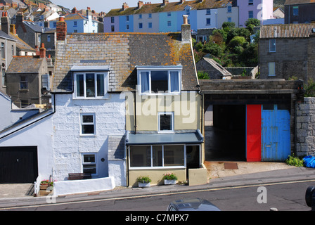 colourful cottages and garage door in Chiswell Portland Dorset England with terrace houses on hill behind Stock Photo