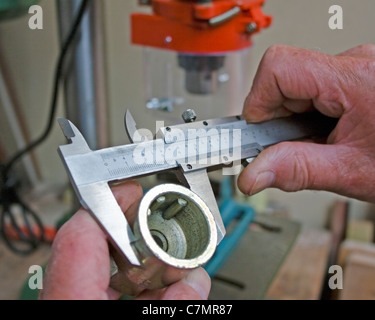 A close-up image shows hands using vernier calipers to measure a socket, ensuring precision in tool measurement. Vernier calipers are commonly used to measure internal and external dimensions with high accuracy. Stock Photo