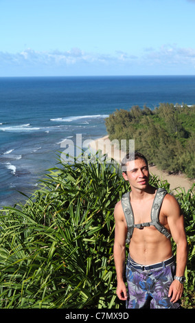 Hiker on the Kalalau Trail on Kauai, with Kee Beach in the background Stock Photo