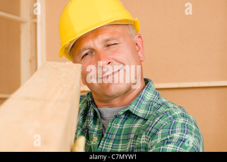 Handyman mature carpenter measures wooden beam for new home improvement Stock Photo