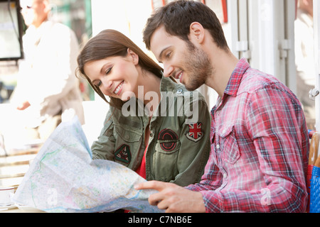 Couple sitting at a sidewalk cafe and reading a map, Paris, Ile-de-France, France Stock Photo
