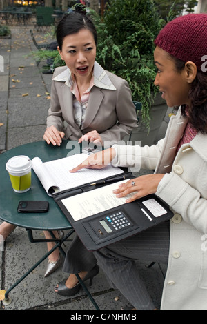 Two young business women discussing a group or team project in the park. Stock Photo
