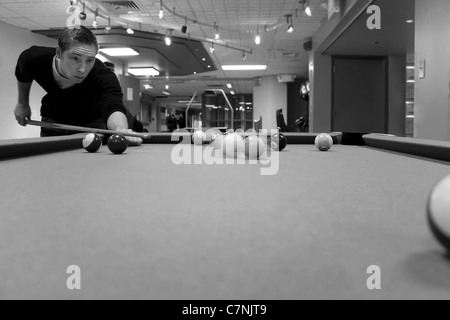 A young man shooting pool with motion blur on the pool balls. Shallow depth of field. Stock Photo