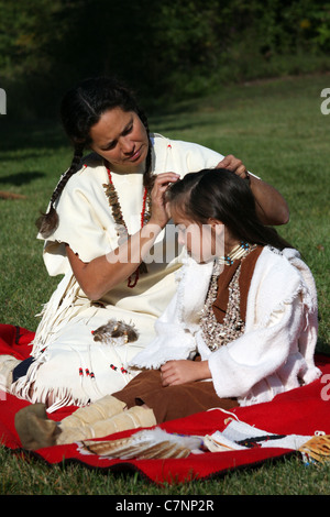 A Native American Indian woman braiding her childs hair Stock Photo