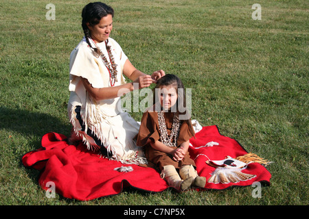 A Native American Indian woman braiding her childs hair Stock Photo