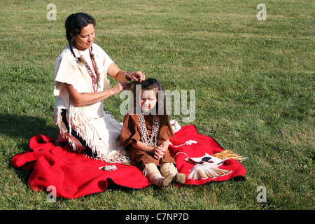 A Native American Indian woman braiding her childs hair Stock Photo