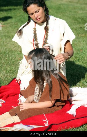 A Native American Indian woman braiding a young childs hair Stock Photo