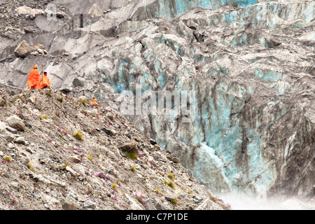 Saffron clad pilgrims walking towards Gaumukh, the edge of the Gangotri Glacier and one of the source of the Ganges river. Stock Photo