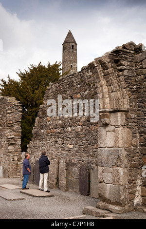 Ireland, Co Wicklow, Glendalough, historic monastic site, visitors in ruined cathedral close to round tower Stock Photo