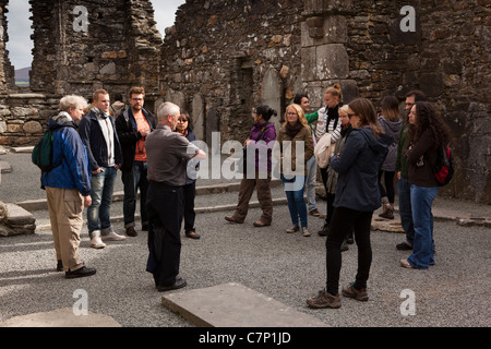 Ireland, Co Wicklow, Glendalough, historic monastic site, group on guided tour inside ruined cathedral Stock Photo