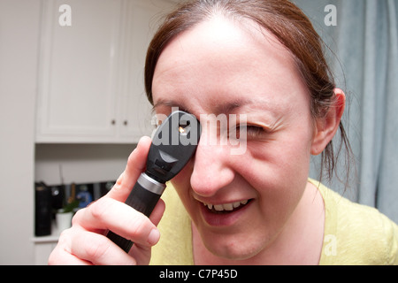 Young doctor examining with an ophthalmoscope Stock Photo