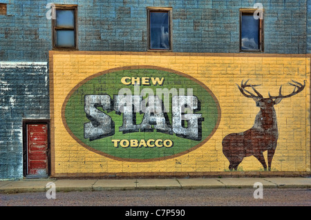 A large antique advertisement for Stag chewing tobacco on the exterior wall of an old abandoned hotel. Stock Photo