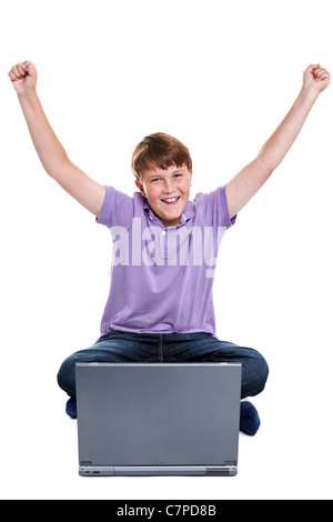 Photo of an 11 year old school boy sat with a laptop computer, his arms raised in the air, isolated on a white background. Stock Photo