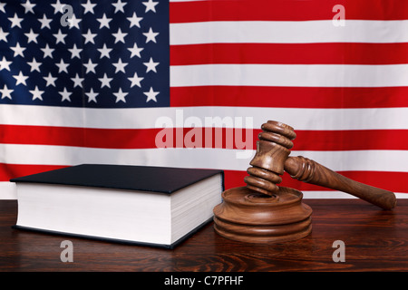 Still life photo of a gavel, block and law book on a judges bench with the American flag behind. Stock Photo