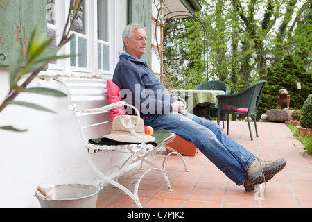 Older man sitting on porch Stock Photo