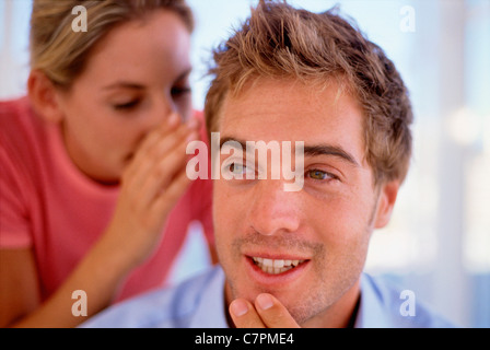 Woman whispering in man’s ear Stock Photo