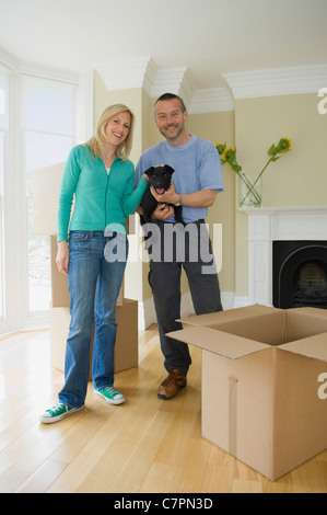 Smiling couple with dog in new home Stock Photo