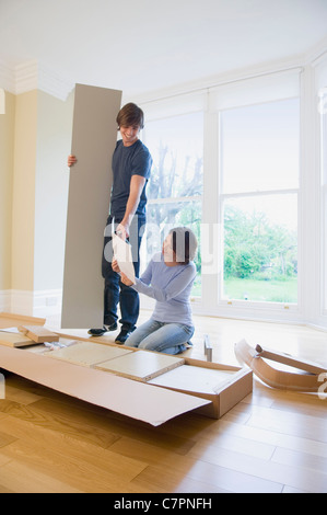 Couple building furniture in new home Stock Photo