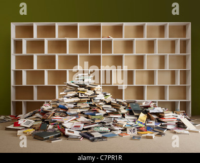 Pile of books by empty shelves Stock Photo