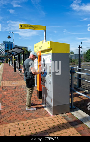 Young man buying ticket to use the Metrolink tram system in Salford ...