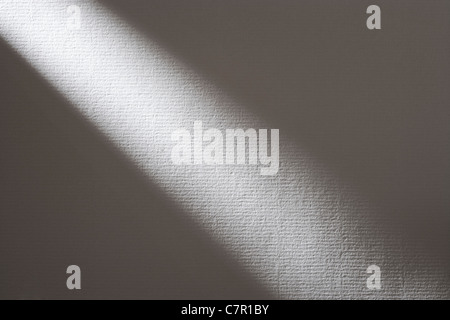 Shaft of light across white textured paper. Stock Photo