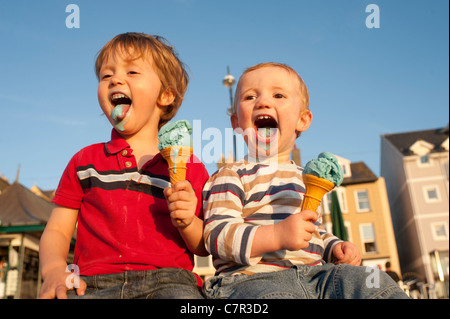 Two young brothers enjoying eating ice cream on Aberystwyth promenade in the late summer sunshine, Wales UK, September 27 2011 Stock Photo