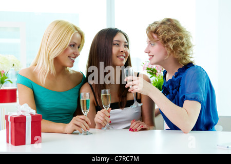 Three young women sitting in cafe and drinking champagne Stock Photo