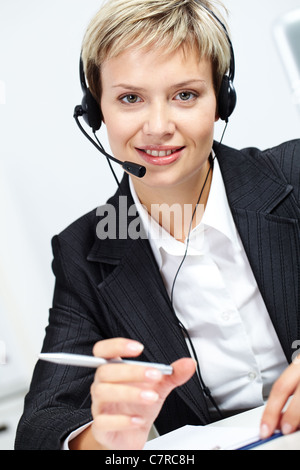 Portrait of young attractive secretary with headset looking at camera and smiling Stock Photo