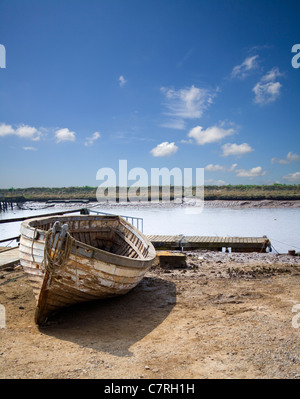 Old wooden hulled fishing boat with winch and sheds on shingle beach ...