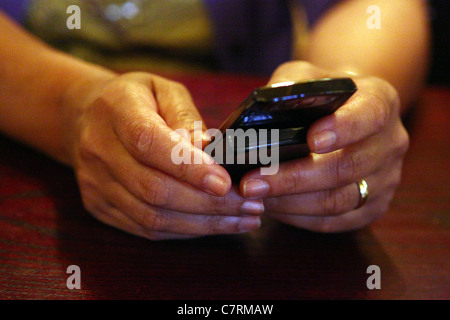 The hands of a mature lady checking her mobile phone Stock Photo
